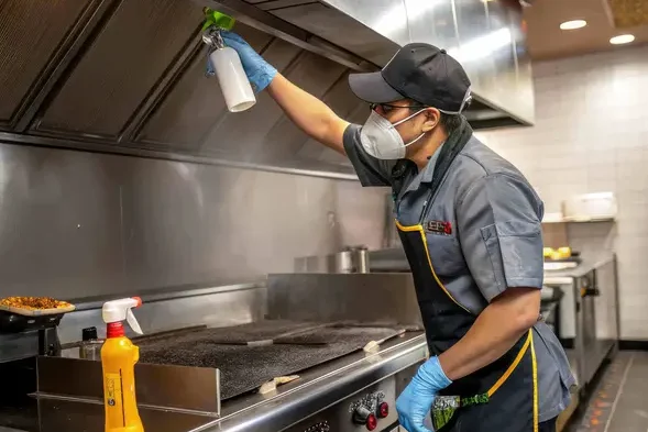 maintenance-worker-cleans-large-kitchen-hood